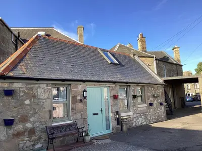 an old stone building with a blue door at Cottage in Mid Calder Village near Edinburgh in Mid Calder
