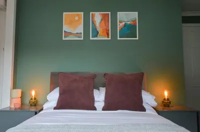 a bedroom with a bed with red pillows and two lamps at Homely 2 Bed House with Private double driveway in Oban