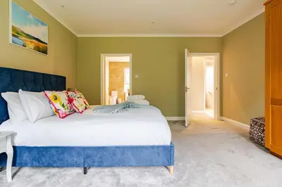 a bedroom with a large bed with a blue headboard at Amulree, Edinburgh City in EDI
