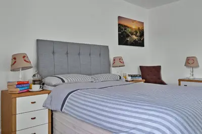 a bedroom with a bed and two lamps and a chair at Finest Retreats - Lochead Cottage in Achahoish