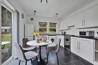 a kitchen with white cabinets and a table and chairs at Finest Retreats - Lochead Cottage in Achahoish