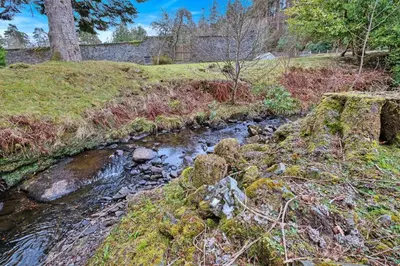 a stream in the middle of a field with grass and trees at Finest Retreats - The Turbine House in Achahoish