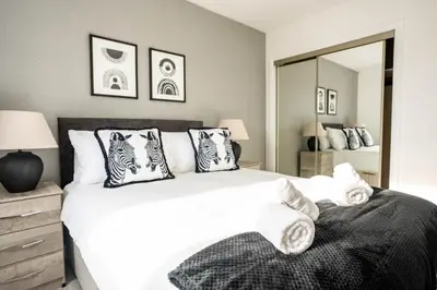 a bedroom with a large white bed and a mirror at Stirling Street Stays in Tillicoultry