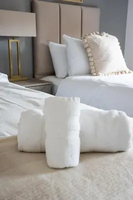 two white towels sitting on top of a bed at Stirling Street Stays in Tillicoultry