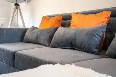 a blue couch with two orange pillows on it at Carradale House in Falkirk
