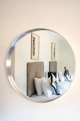 a circular mirror hanging on a wall with pillows at Carradale House in Falkirk