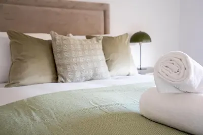 a white bed with a rolled up towel on it at Carradale House in Falkirk