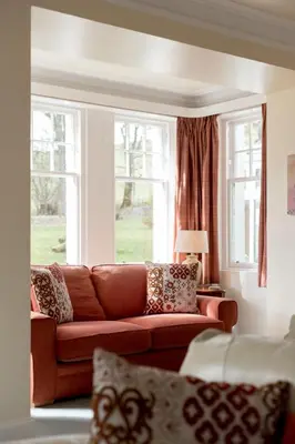 a living room with a couch and two windows at Holiday Home Balcraig House by Interhome in Straiton