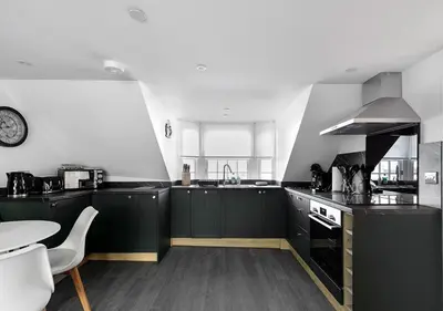 a kitchen with black cabinets and a table and a clock at Castle Street Apartments - Luxury Kilchattan Apartment in Rothesay
