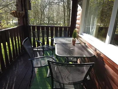 a porch with four chairs and a table and a window at Stravaigin Lodges in Rashfield