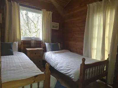 a bedroom with two beds in a log cabin at Stravaigin Lodges in Rashfield
