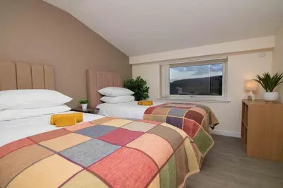 two beds in a room with a window at Edenmill Farm in Glasgow