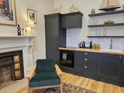 a kitchen with black cabinets and a green chair at Comely Bank Coorie in Edinburgh