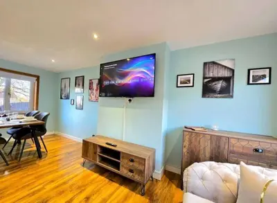 a living room with a couch and a tv on the wall at Super luxury 2 bedroom, full house sleep 5 with garden & parking close to airport in Elderslie