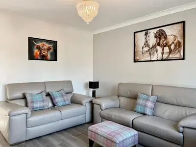 a living room with two couches and a chandelier at Cambusmoon Apartment in Gartocharn