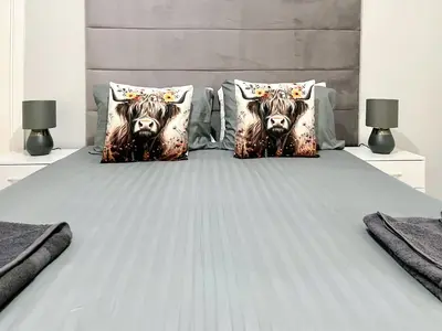 a bed with two cow pillows on it at Cambusmoon Apartment in Gartocharn