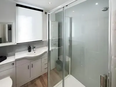 a bathroom with a glass shower and a sink at Cambusmoon Apartment in Gartocharn