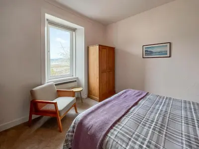 a bedroom with a bed and a chair and a window at Glenfyne Apartment - Uk49318 in Ardrishaig