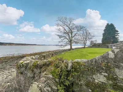 a stone wall with a tree on the side of the water at Glenfyne Apartment - Uk49318 in Ardrishaig