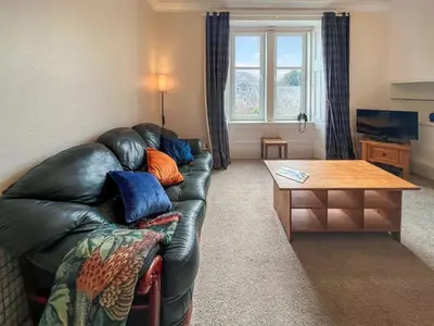 a living room with a leather couch and a table at Glenfyne Apartment - Uk49318 in Ardrishaig