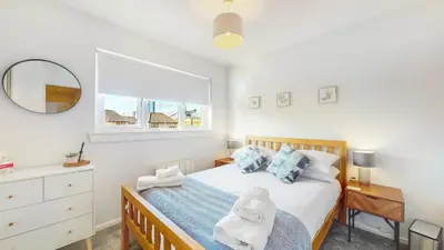 a bedroom with a bed and a mirror and a window at Cairn BNB Introduces Mavisbank Gardens - where homely charm meets modern living in Glasgow