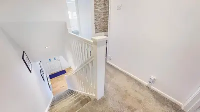 a hallway with a staircase with white walls and wood floors at Cairn BNB Introduces Mavisbank Gardens - where homely charm meets modern living in Glasgow