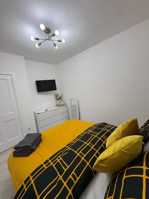 a bedroom with a bed with a yellow and black blanket at Cozy 3 Bed Home, Free Parking 8 min to City Centre in Cowlairs