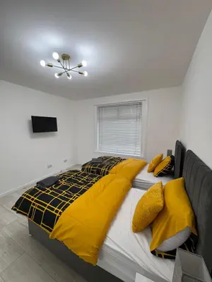 a bedroom with a large bed with yellow blankets and pillows at Cozy 3 Bed Home, Free Parking 8 min to City Centre in Cowlairs
