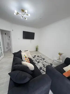 a living room with a black couch and a tv at Cozy 3 Bed Home, Free Parking 8 min to City Centre in Cowlairs