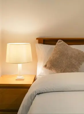 a bed with a lamp on a wooden night stand at b&b in Edinburgh in Edinburgh