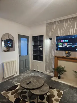 a living room with a table and a fireplace at Addex Apartment in Dunfermline