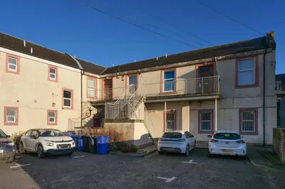 two cars parked in a parking lot in front of a building at Central 1-bed flat - Walk to shops, pubs and station in Saltcoats