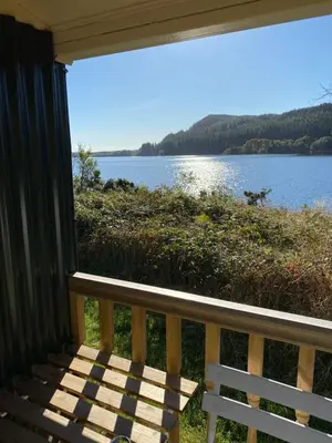 a porch with a bench and a view of a lake at The Secret Shepherds Hut- Off Grid Retreat in New Galloway