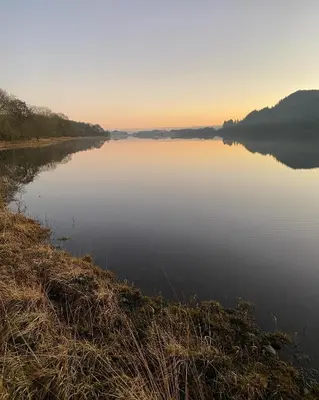 a view of a large lake at sunset at The Secret Shepherds Hut- Off Grid Retreat in New Galloway