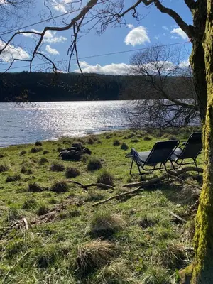 a couple of chairs sitting next to a lake at The Hidden Shepherds Hut- Off Grid Retreat in Castle Douglas