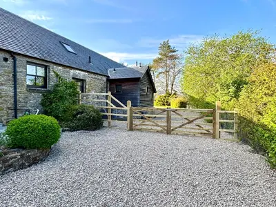 a stone house with a wooden fence in front of it at The Bothy, Callander in Callander