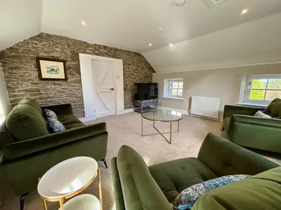 a living room with green furniture and a brick wall at The Bothy, Callander in Callander