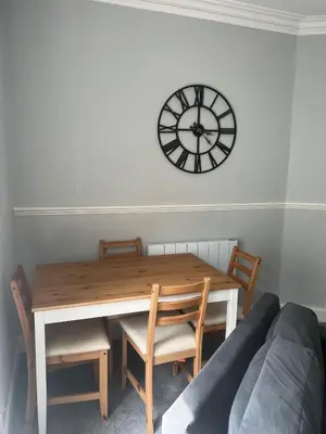 a dining room table with chairs and a clock on the wall at Our Salad Days Lochgilphead in Lochgilphead
