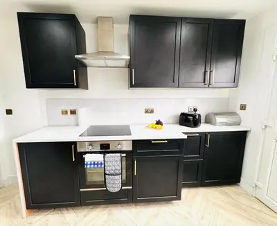 a kitchen with black cabinets and white counter tops at Luxury Grangemouth accomodation with free parking in Falkirk