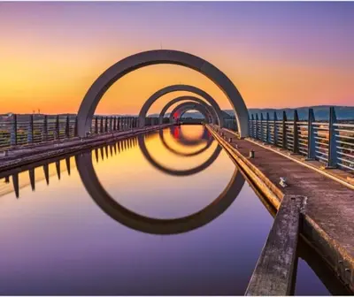 a reflection of a bridge in the water at sunset at Luxury Grangemouth accomodation with free parking in Falkirk