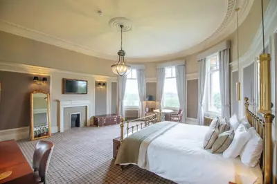 a large bedroom with a bed and a fireplace at Cornhill Castle in Biggar