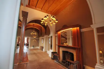 a hallway with a fireplace and a chandelier at Cornhill Castle in Biggar