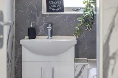 a bathroom with a white sink and a black wall at Highfield Apartment- 2 Bed in Motherwell close to centre in Motherwell