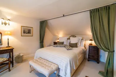 a bedroom with a large bed with green curtains at The Royal Hotel in Comrie