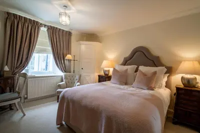 a bedroom with a bed and a chair and a window at The Royal Hotel in Comrie