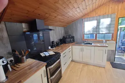 a large kitchen with a stove and a sink at Wildwood Cabin - Sleeps 6 Hot Tub & Parking in Beattock