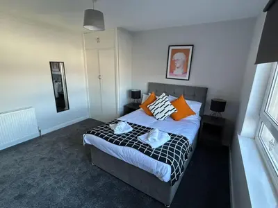a bedroom with a bed with orange and white pillows at 3-Bed Apartment Central Greenock in Greenock