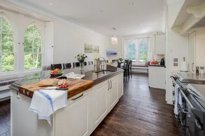 a kitchen with white cabinets and a wooden counter top at Sequoia House in Tarbet