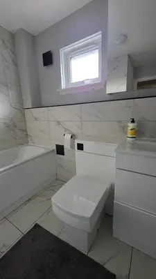 a bathroom with a toilet and a tub and a window at The Ansi8 in Livingston