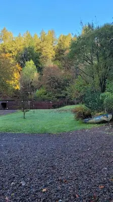 a grassy field with a wooden fence and trees at Squirrels Wood Lodge, nr Glencoe, dog friendly in Acharra